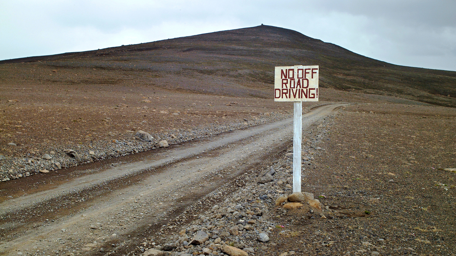 View of a rocky track in Iceland’s Highlands with a sign warning against off-road driving.