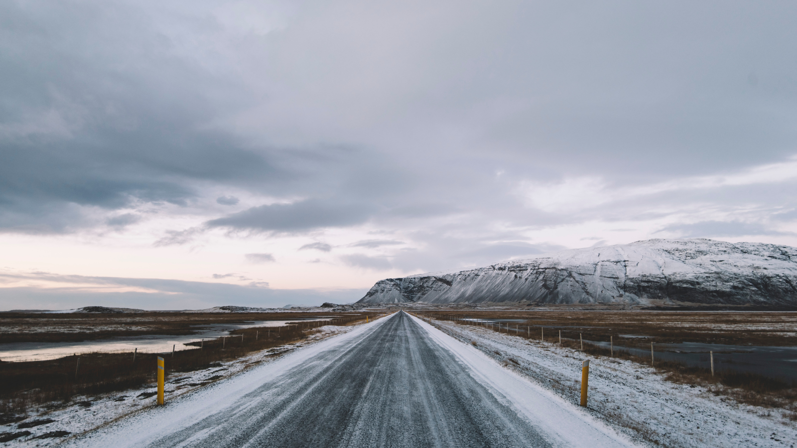 An icy road in Iceland reaching towards a snow-covered mountain on the horizon.