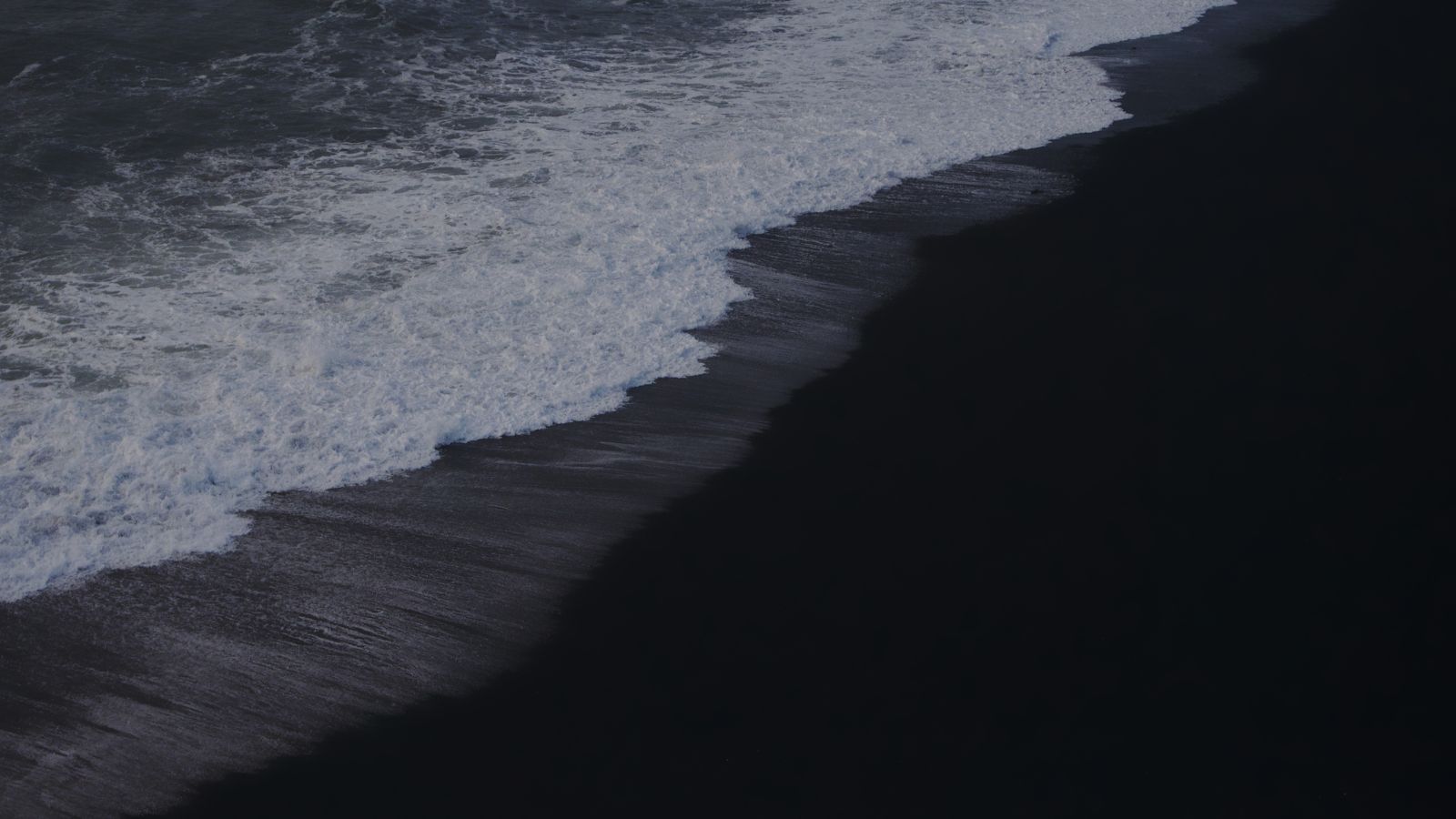 Black sand and shoreline at Reynisfjara beach in Iceland.