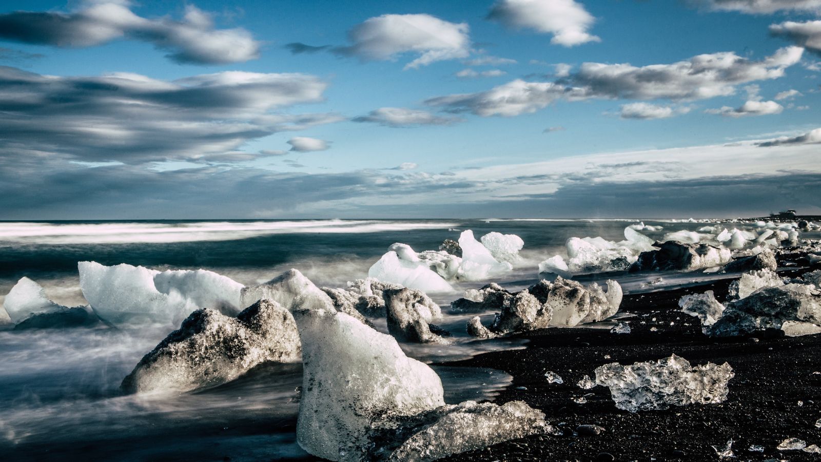 Diamond Beach in South Iceland beneath a blue sky with clouds. 