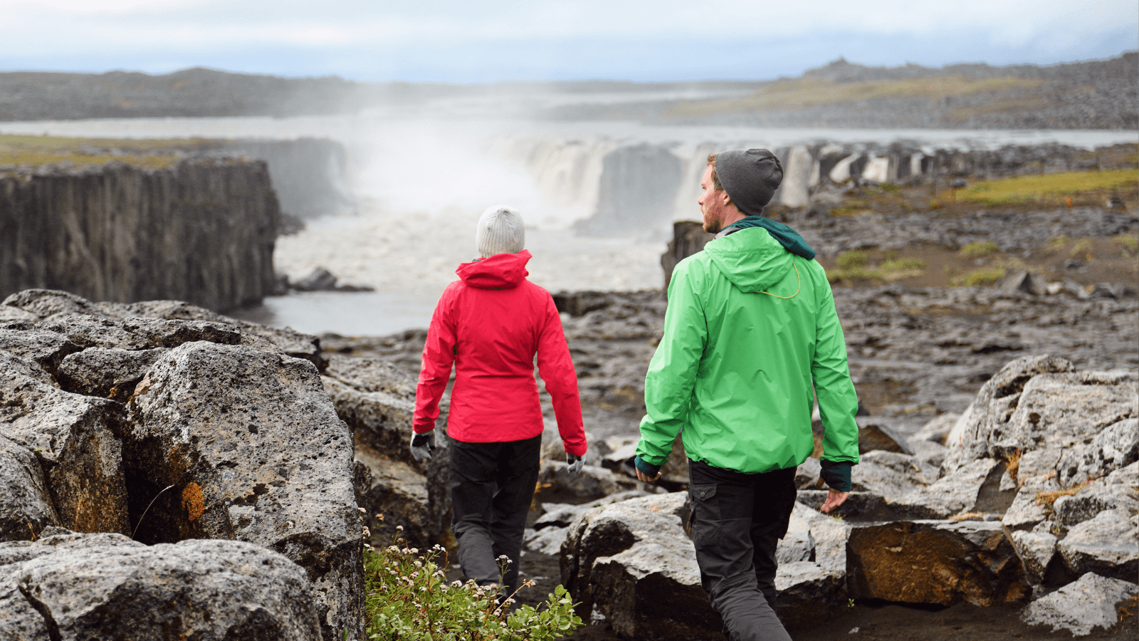 Tourists walking towards a waterfall in Iceland. 