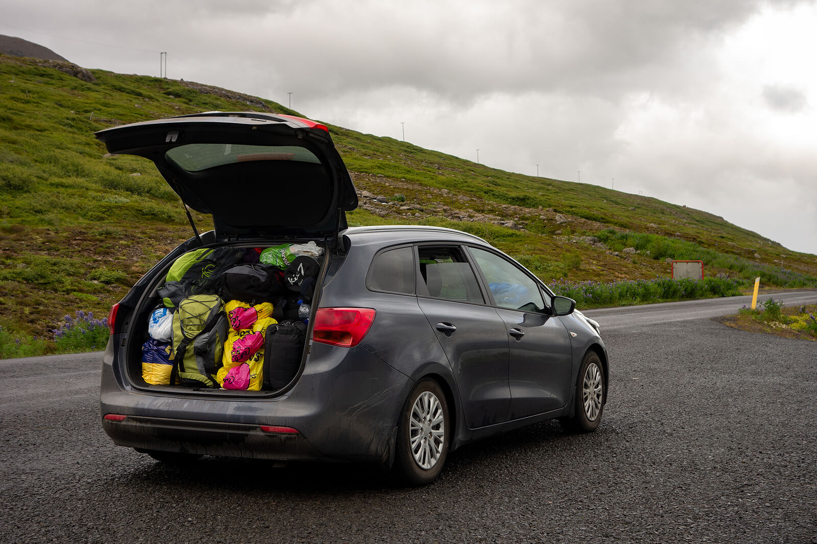 Hatchback car packed with camping and hiking equipment alongside a road in Iceland.