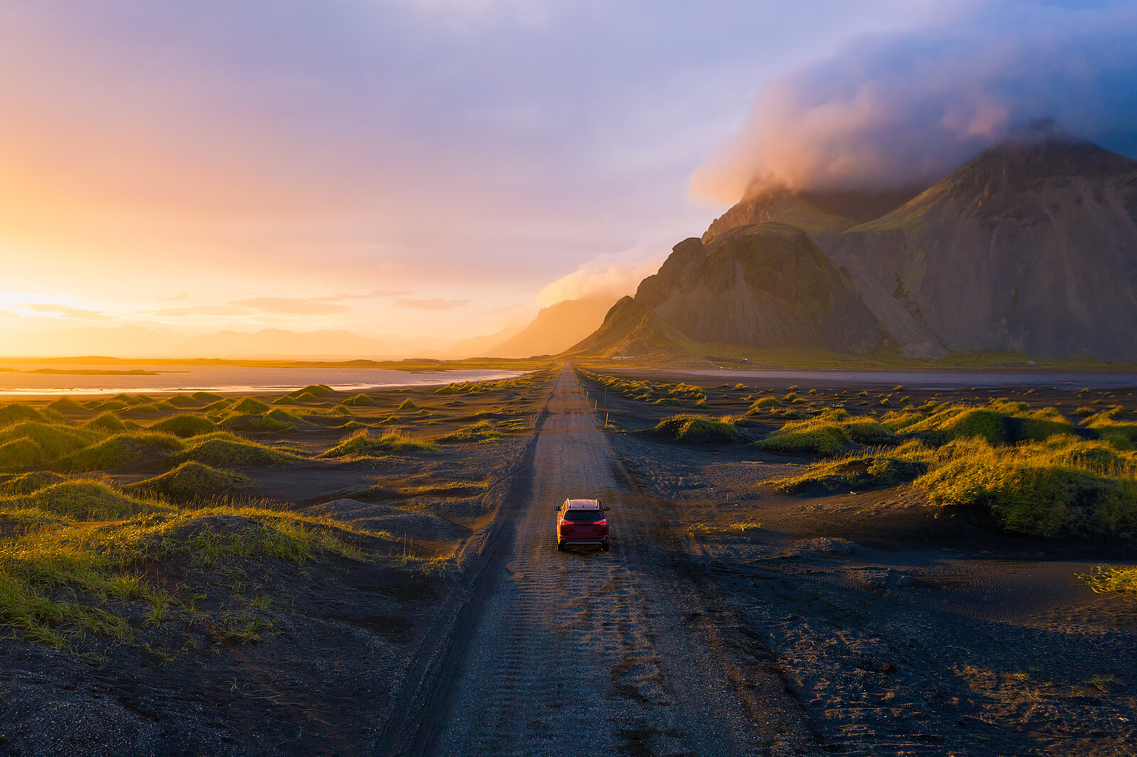 An SUV driving on a dirt road near Vestrahorn, Iceland.